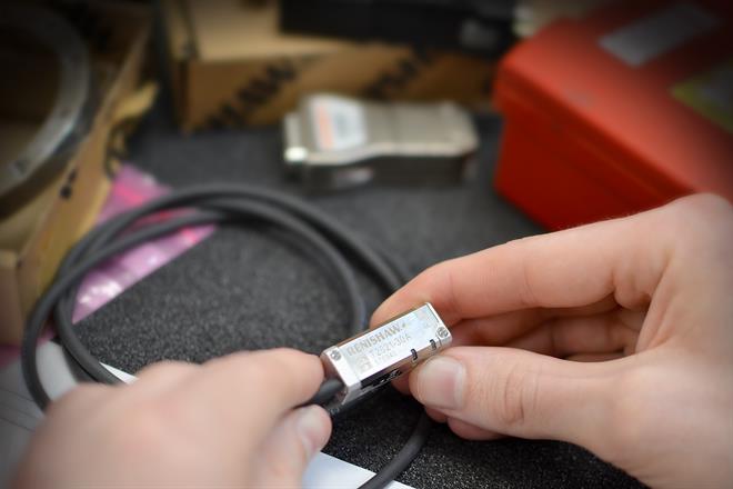 Two hands holding a TONiC™ optical encoder with a cable