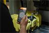 Hand holding mobile device displaying spherical deviation in CARTO Ballbar Connect app, with QC20 ballbar in background